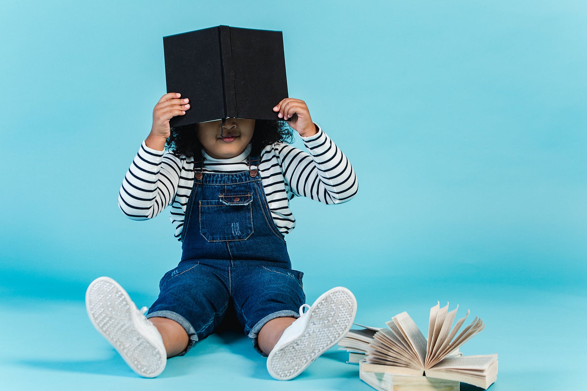 small black girl sitting on floor with books in studio